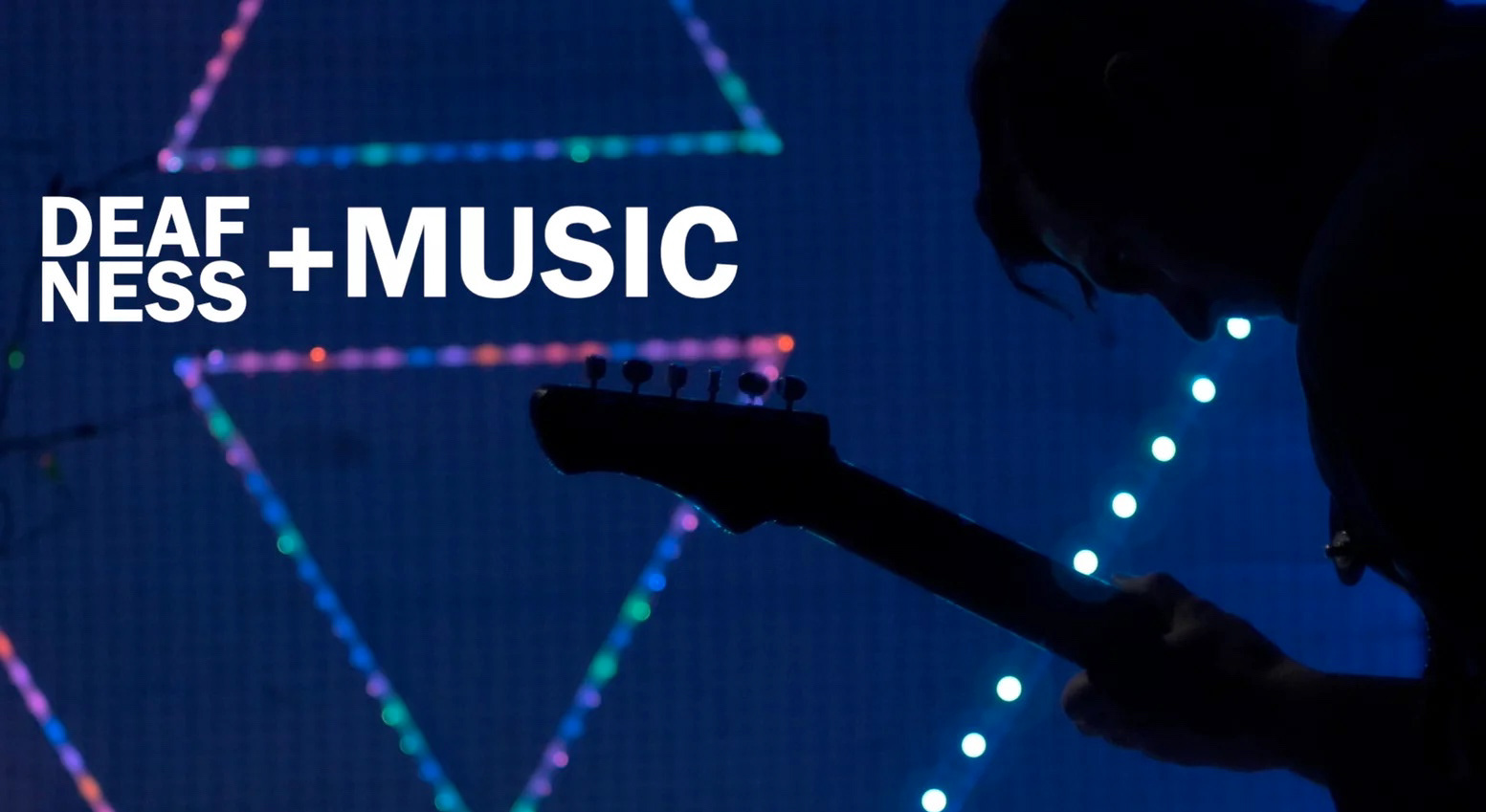 Bold white type reading "DEAFNESS + MUSIC" across a deep blue LED video wall patterned with pink, teal and orange triangle outlines; at right, a long-haired figure is silhouetted leaning over the headstock of a bass guitar, a vertical run of bright white LEDs falling beside them
